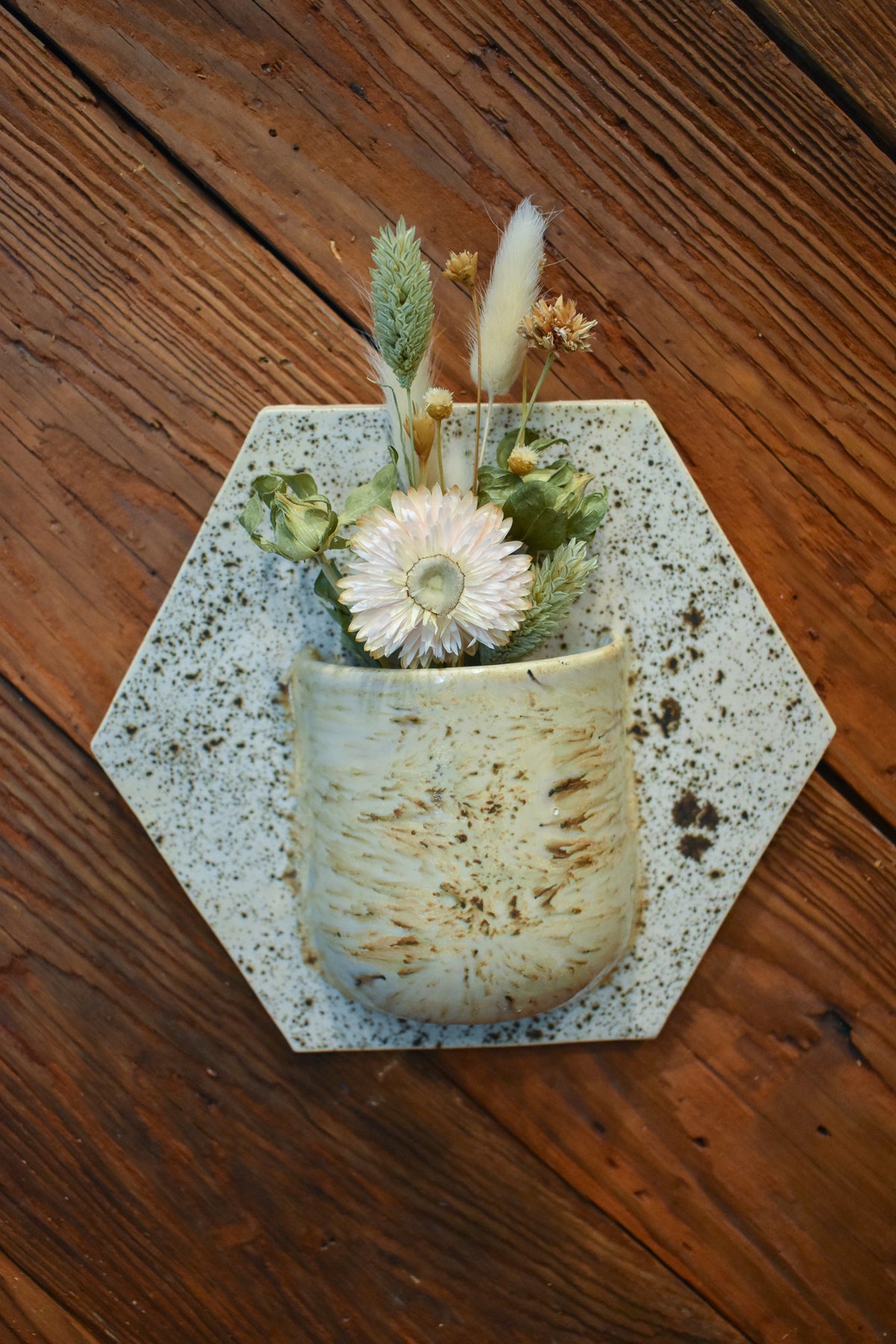 Medium hand-formed wall vase in Pebble, a speckled cream pocket on a pale hexagon back plate