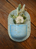 Medium hand-formed wall vase in Patch of Sky, a sky-blue speckled pocket on a rounded cream back plate