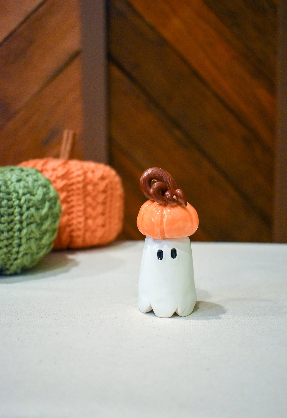 Hand-sculpted ceramic ghost wearing a pumpkin for a hat