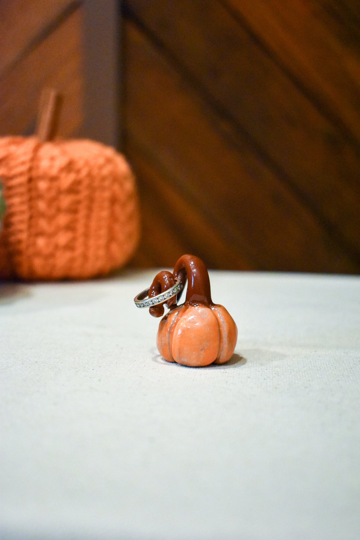 Hand-sculpted ceramic pumpkin in glossy persimmon orange with a curl of rust-brown vine