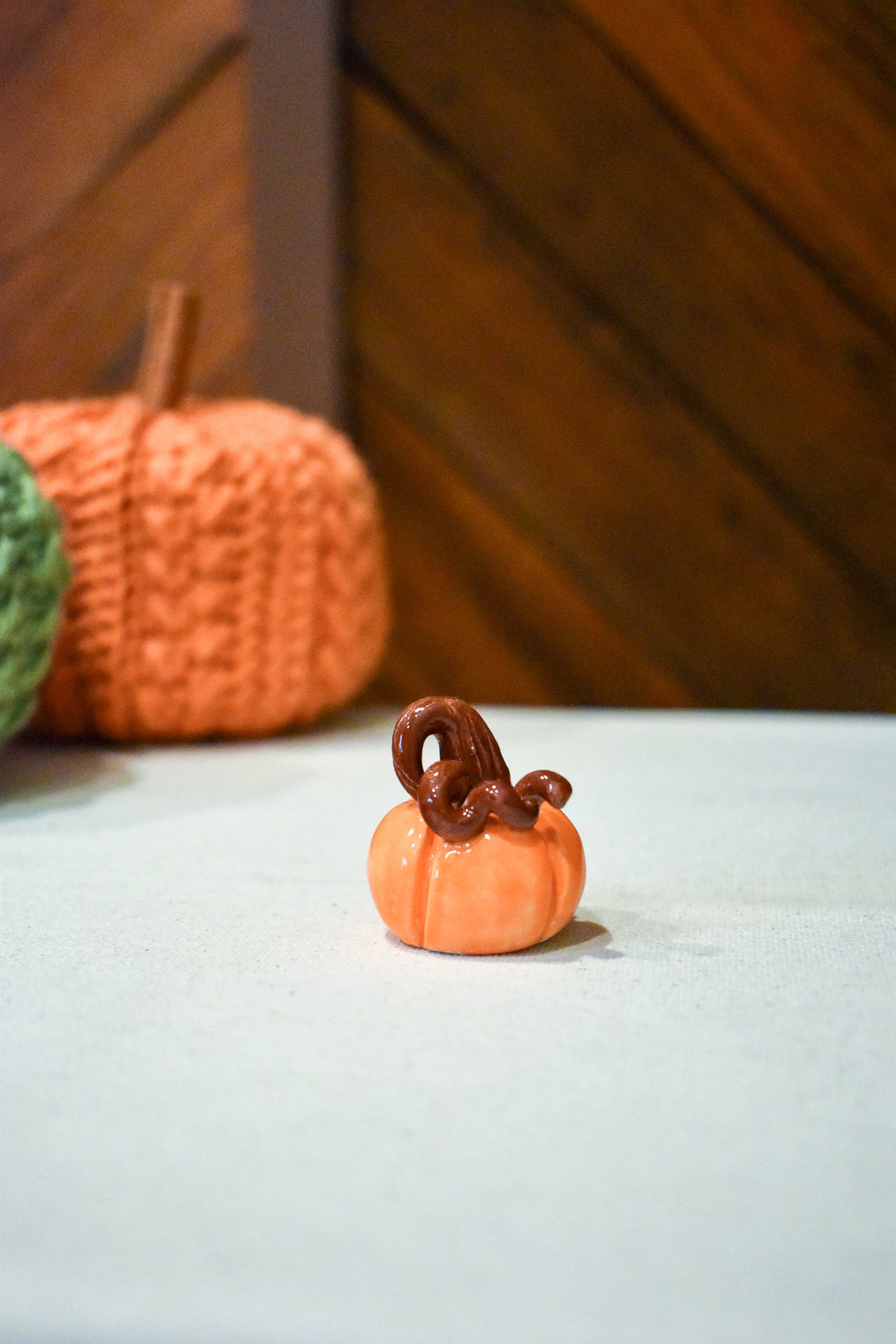 Hand-sculpted ceramic pumpkin in glossy persimmon orange with a curl of rust-brown vine