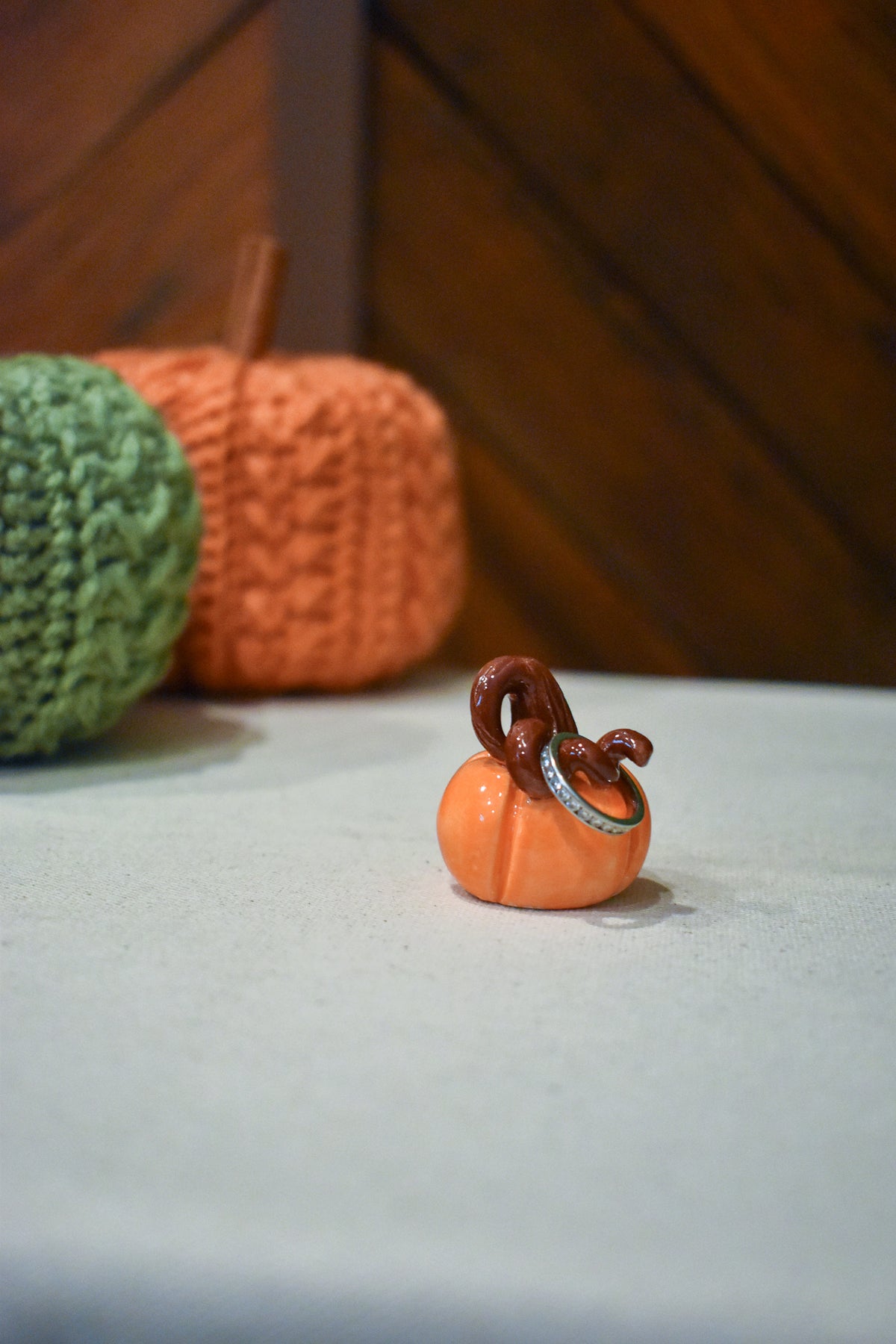 Hand-sculpted ceramic pumpkin in glossy persimmon orange with a curl of rust-brown vine