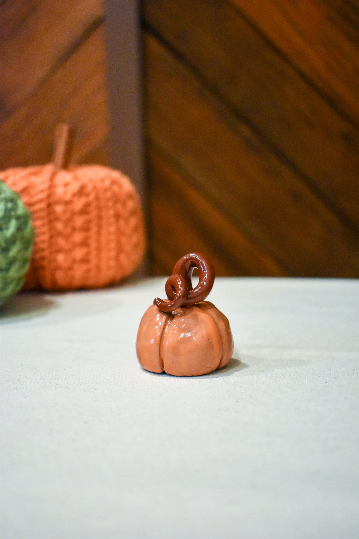 Hand-sculpted ceramic pumpkin in glossy persimmon orange with a curl of rust-brown vine