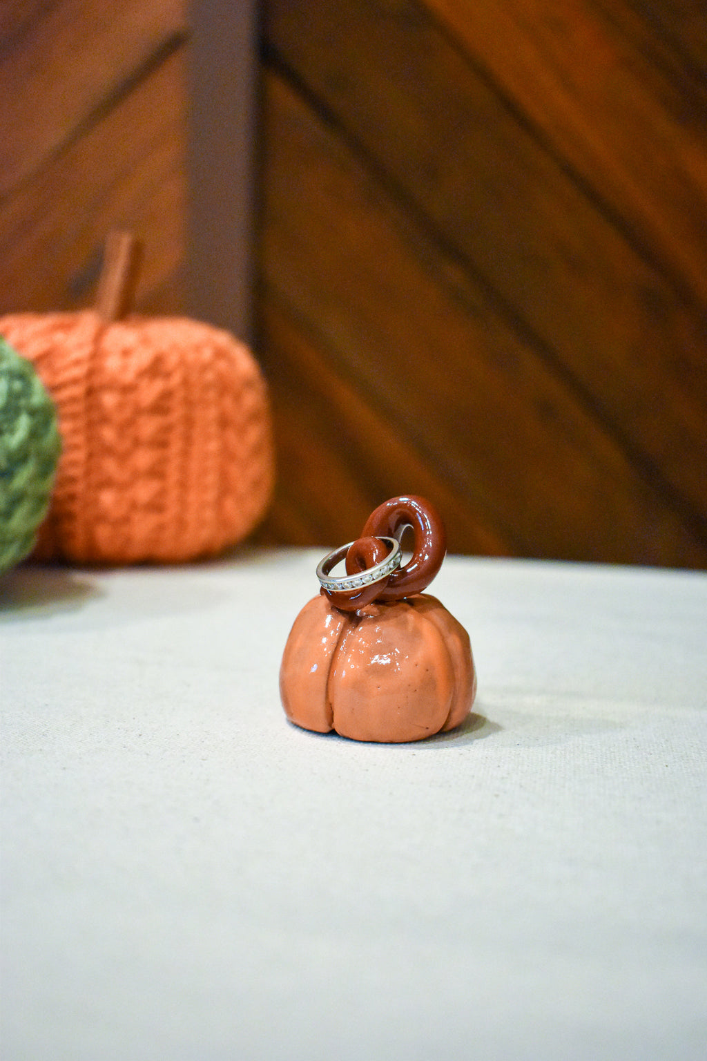 Hand-sculpted ceramic pumpkin in glossy persimmon orange with a curl of rust-brown vine