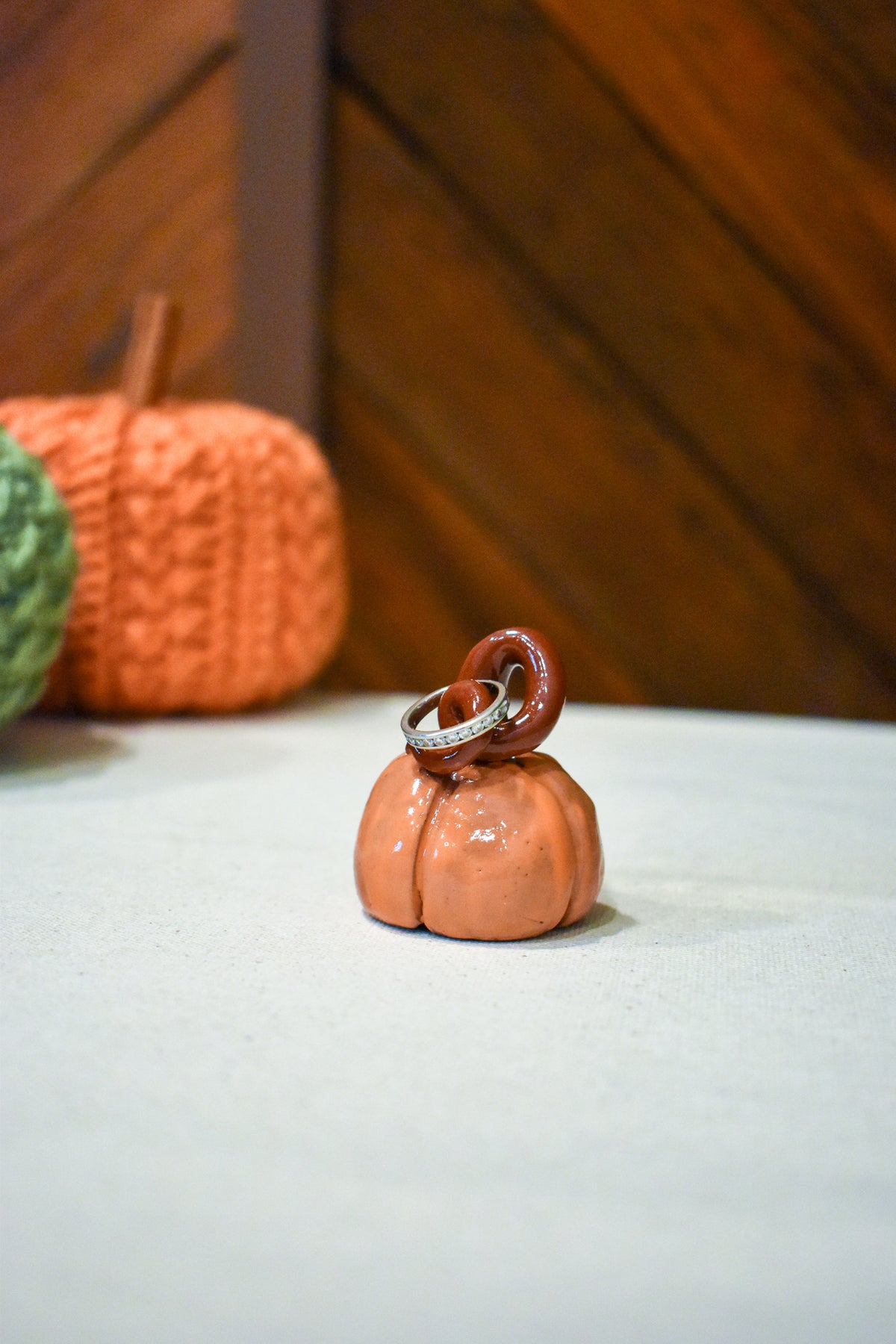 Hand-sculpted ceramic pumpkin in glossy persimmon orange with a curl of rust-brown vine