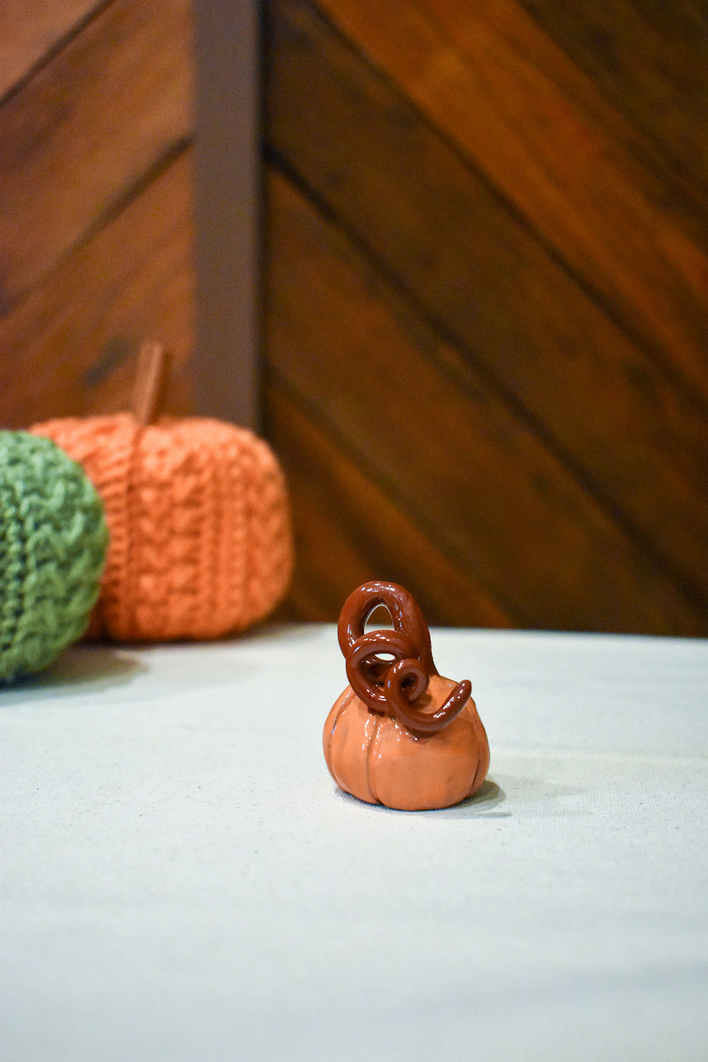 Hand-sculpted ceramic pumpkin in glossy persimmon orange with a curl of rust-brown vine