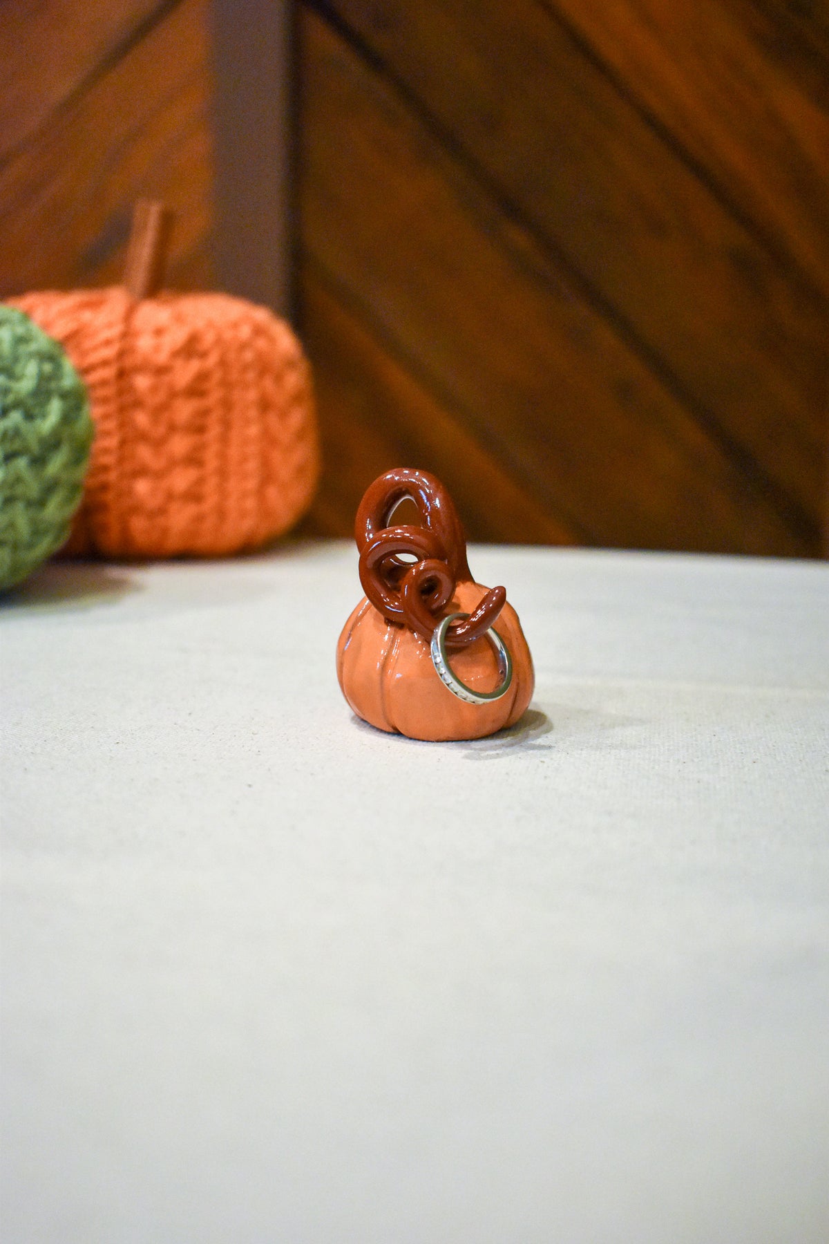 Hand-sculpted ceramic pumpkin in glossy persimmon orange with a curl of rust-brown vine