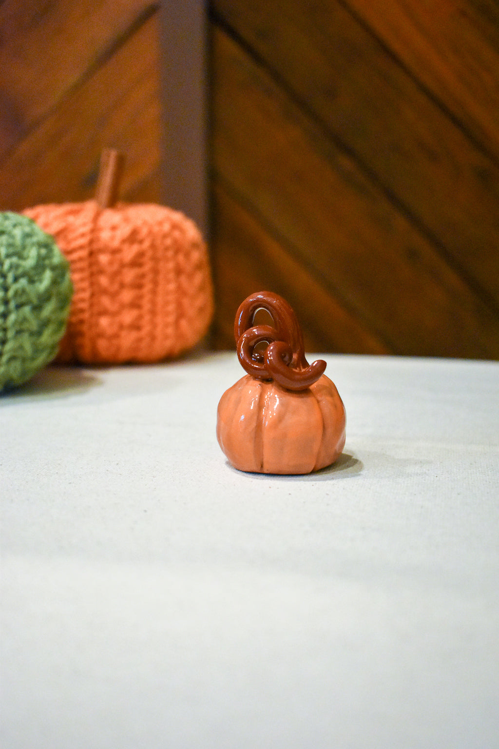 Hand-sculpted ceramic pumpkin in glossy persimmon orange with a curl of rust-brown vine