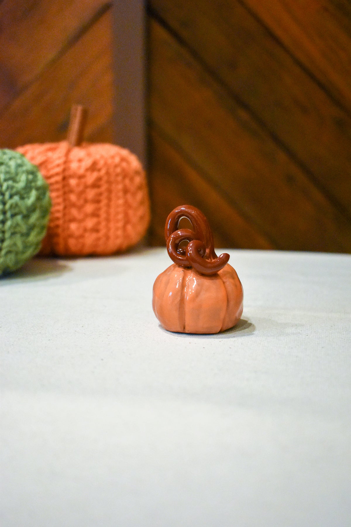 Hand-sculpted ceramic pumpkin in glossy persimmon orange with a curl of rust-brown vine