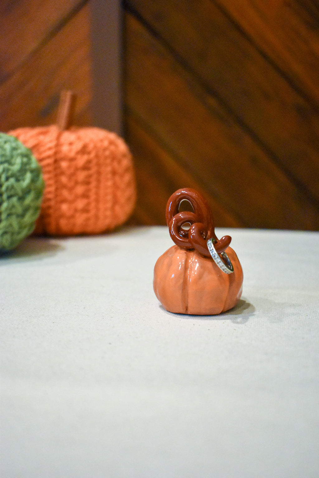 Hand-sculpted ceramic pumpkin in glossy persimmon orange with a curl of rust-brown vine
