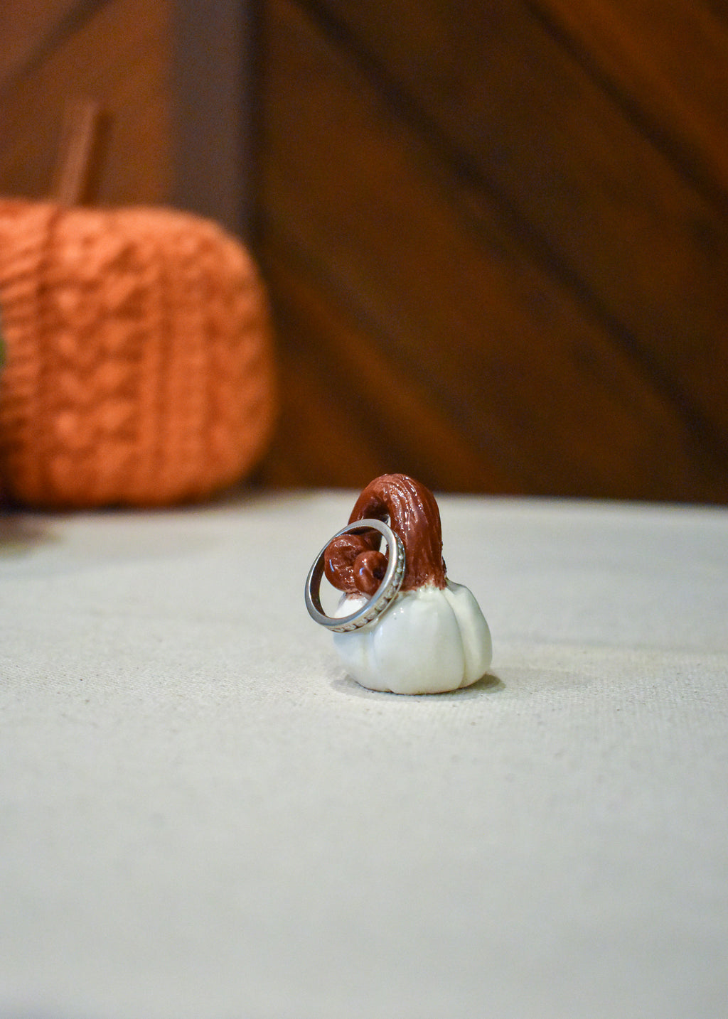 Tiny hand-sculpted ceramic pumpkin in glossy moonstone white with a curl of rust-brown vine