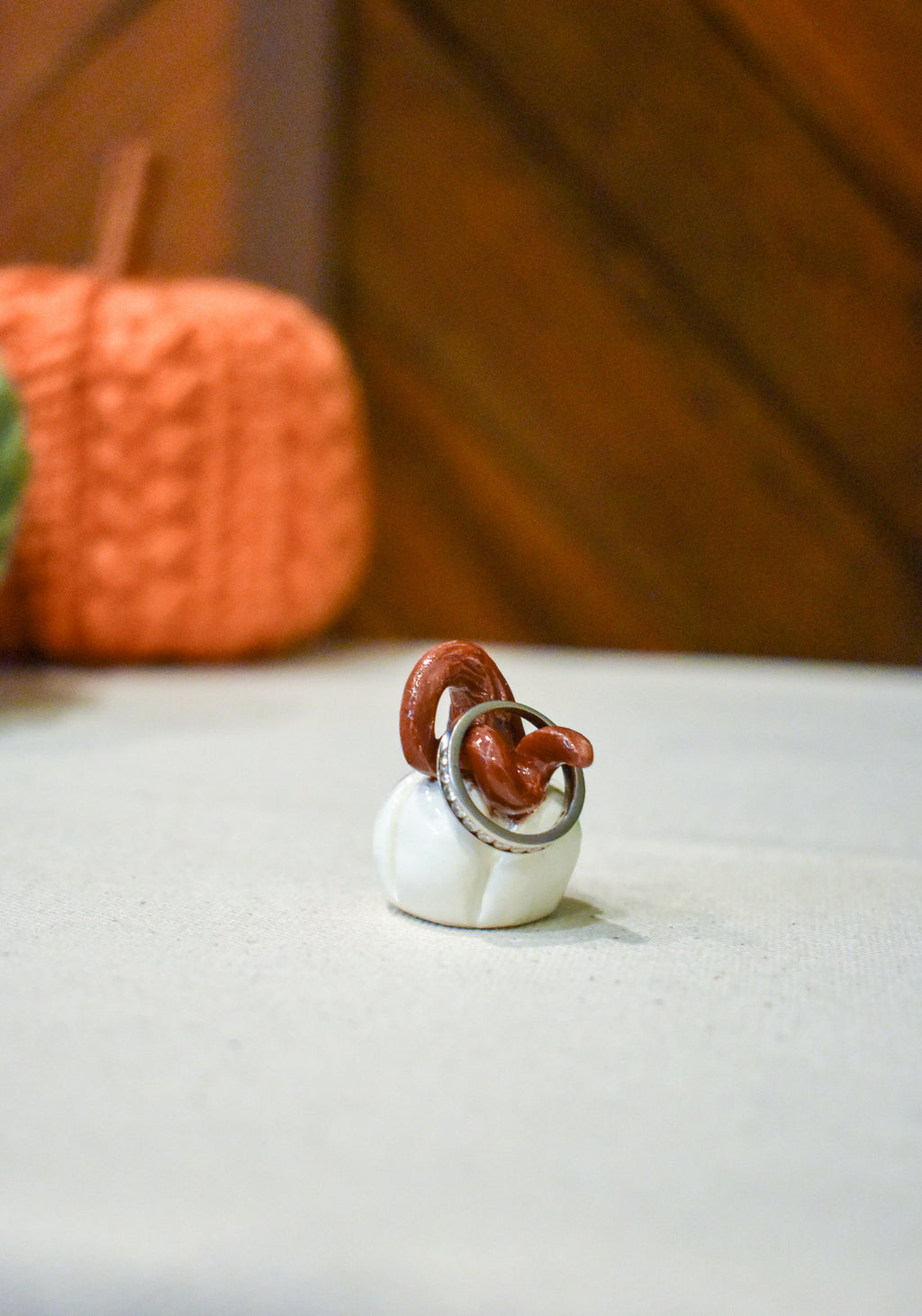 Tiny hand-sculpted ceramic pumpkin in glossy moonstone white with a curl of rust-brown vine