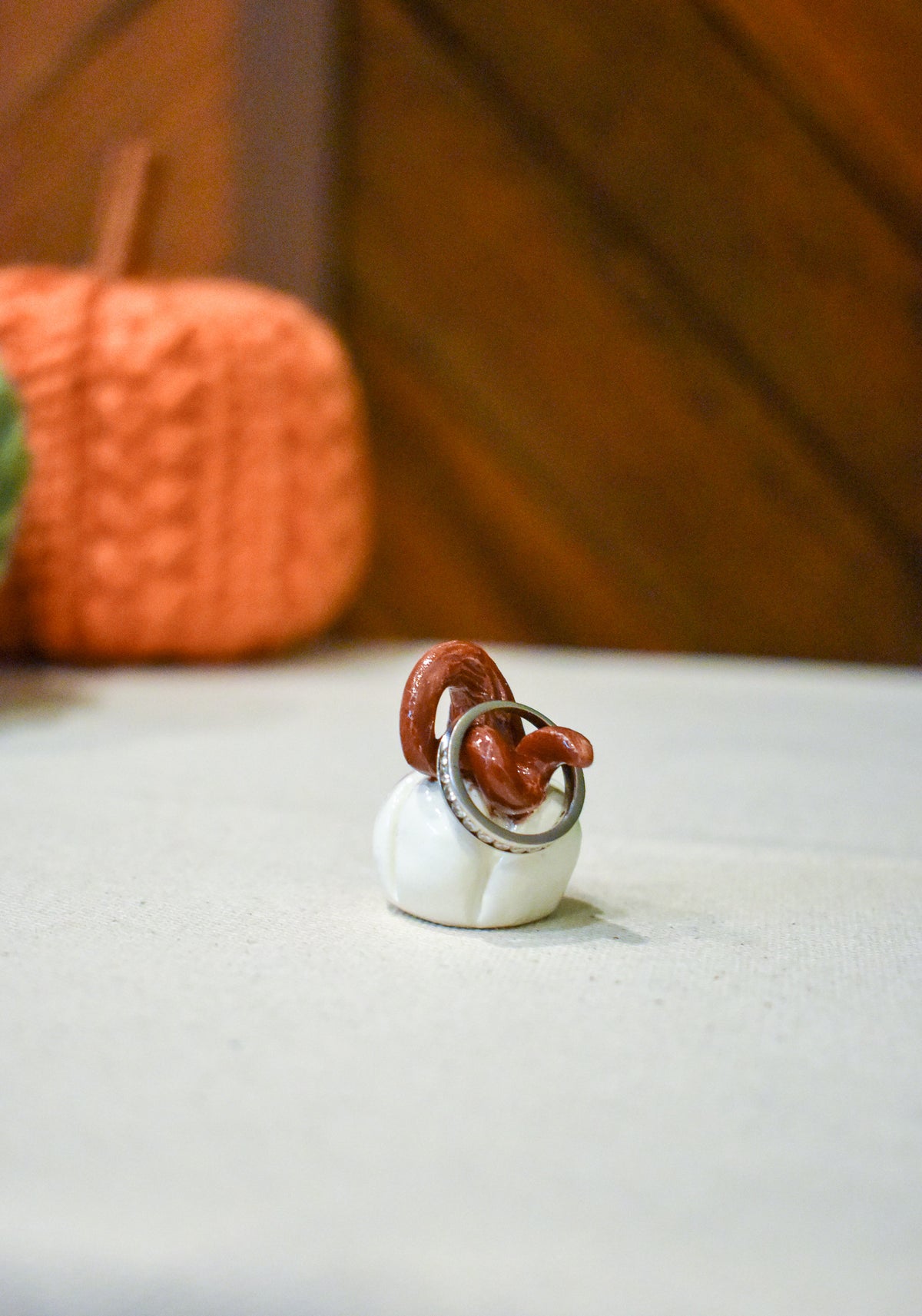 Tiny hand-sculpted ceramic pumpkin in glossy moonstone white with a curl of rust-brown vine