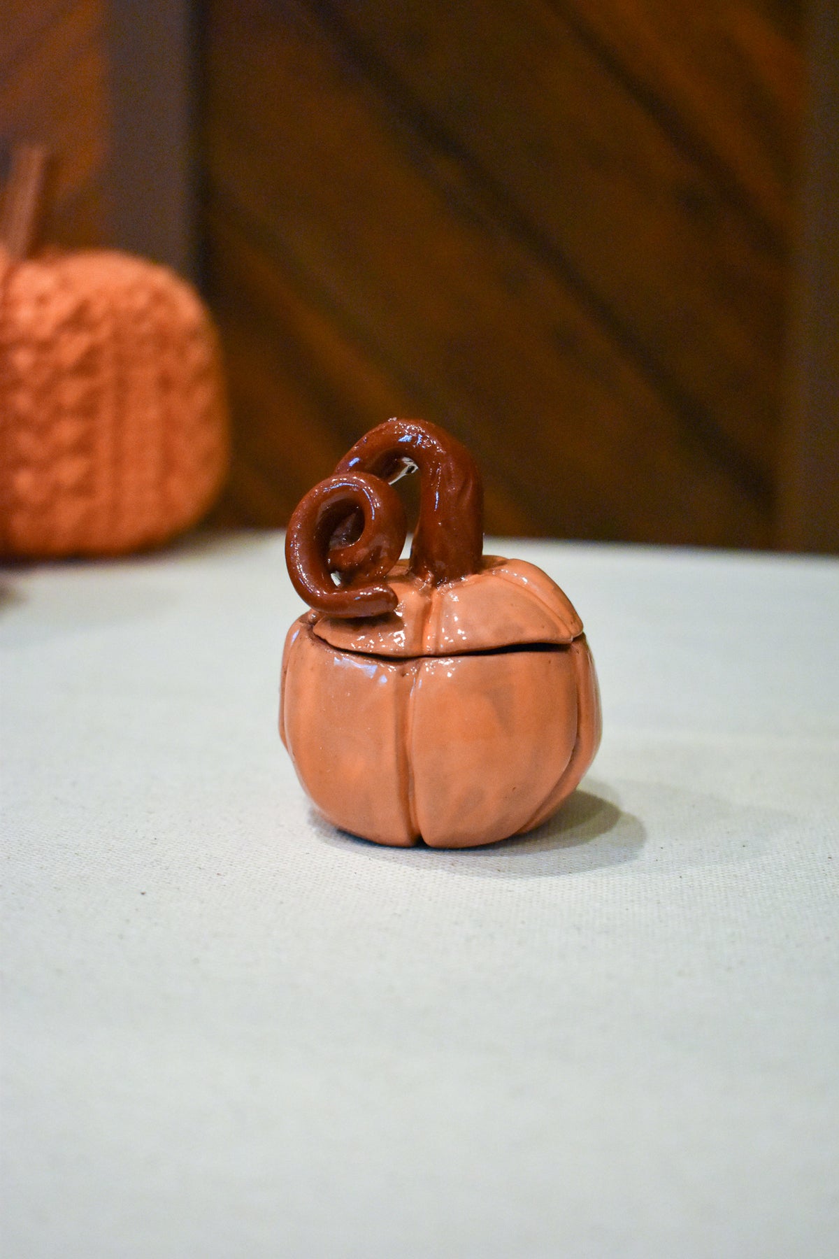 Hand-sculpted ceramic pumpkin jar with a lift-off lid, in glossy persimmon orange