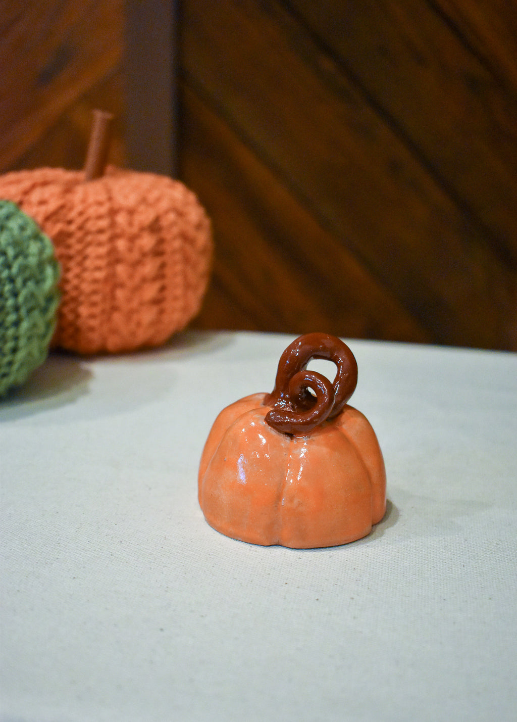 Hand-thrown ceramic pumpkin in glossy persimmon orange with a curl of rust-brown vine