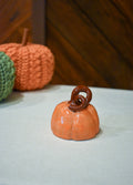 Hand-thrown ceramic pumpkin in glossy persimmon orange with a curl of rust-brown vine