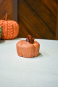 Hand-thrown ceramic pumpkin in glossy persimmon orange with a curl of rust-brown vine