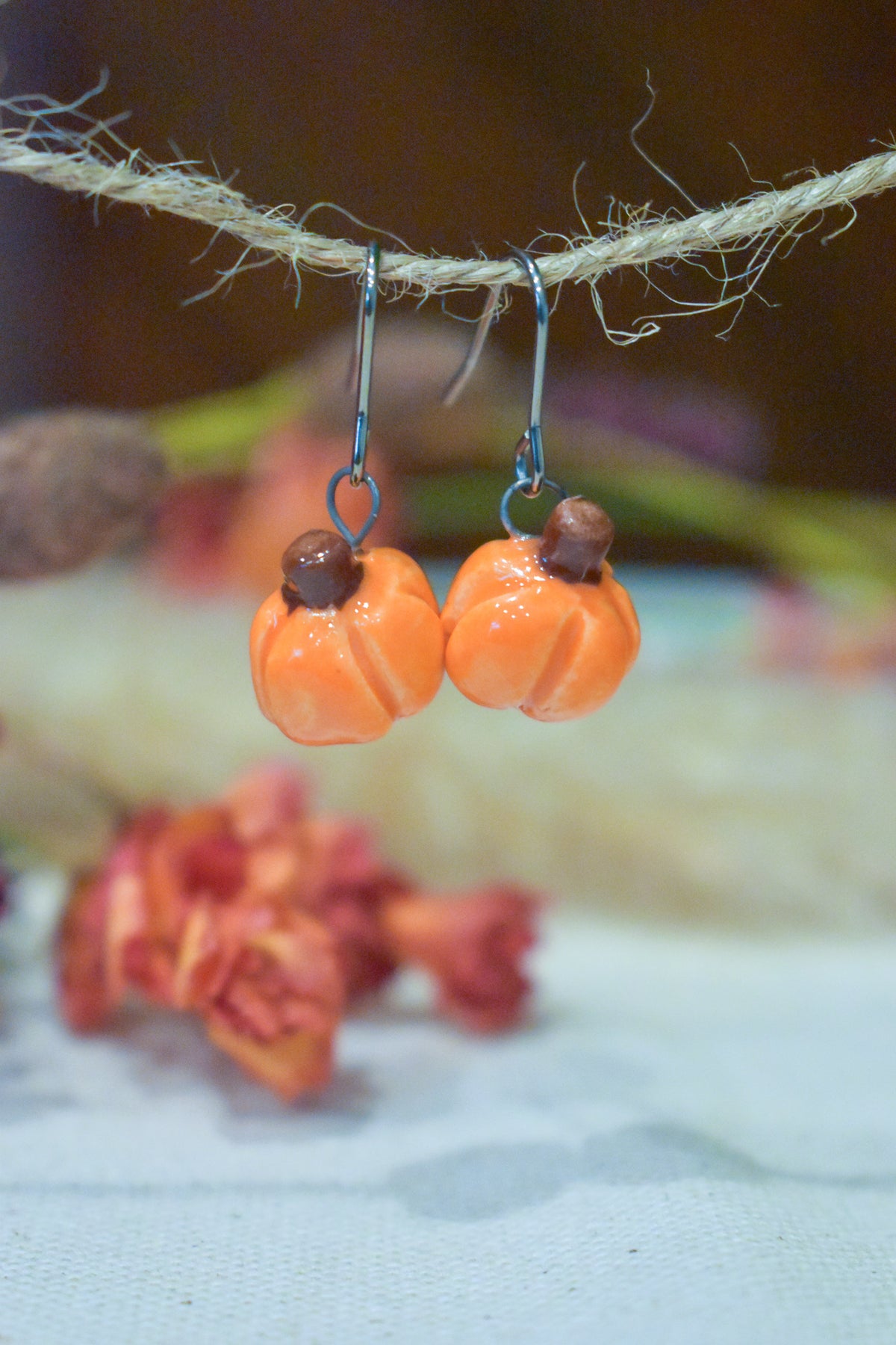 Tiny hand-sculpted ceramic pumpkin earrings in glossy persimmon orange on titanium hooks