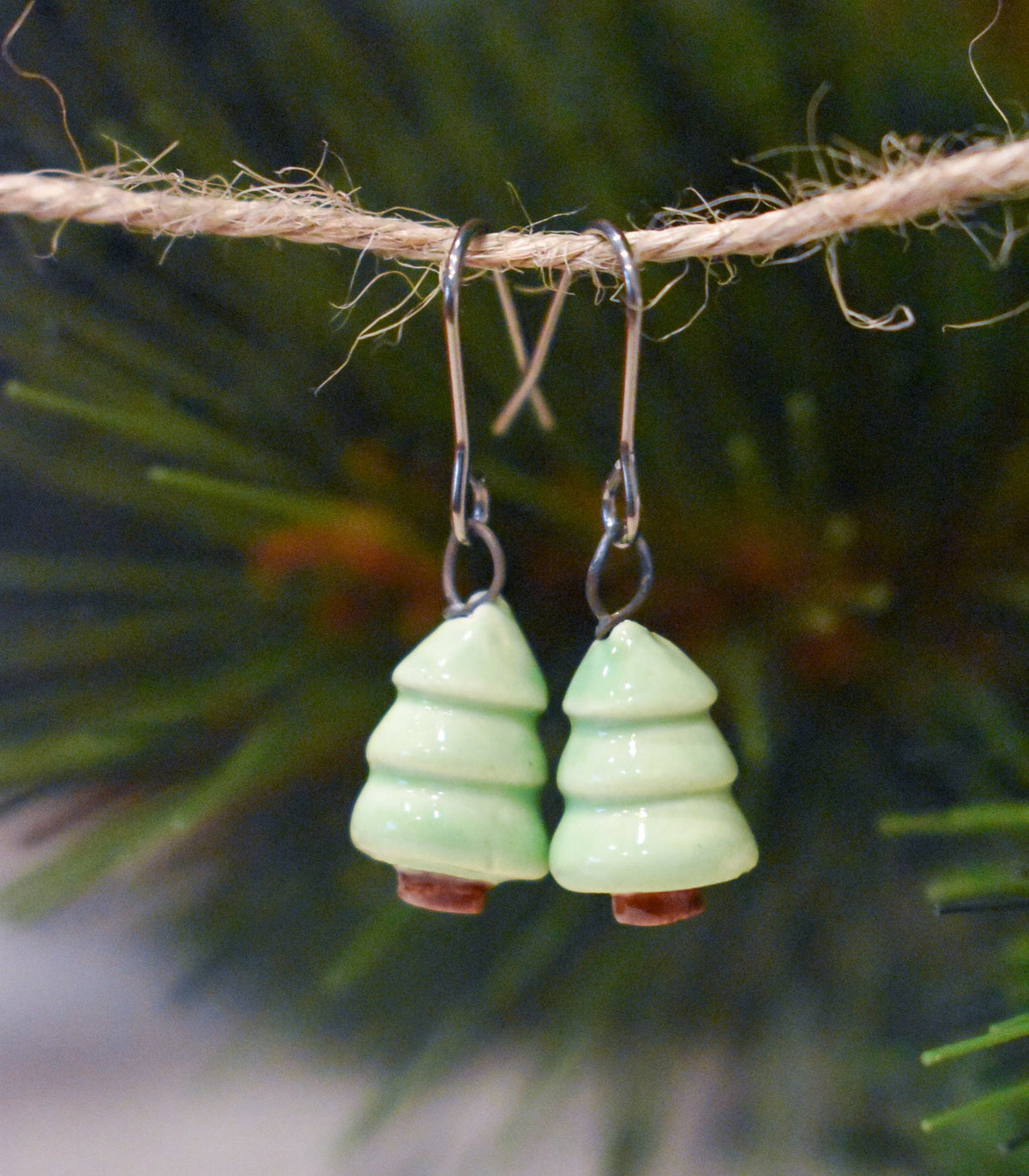 Tiny hand-sculpted ceramic evergreen earrings in pistachio green on titanium hooks
