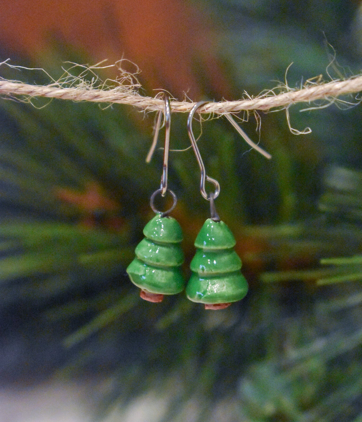 Tiny hand-sculpted ceramic evergreen earrings in fern green on titanium hooks