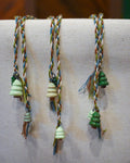 Hand-braided bookmark with hand-sculpted ceramic trees on a braided cord in green, blue, white, and brown