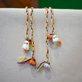 Hand-braided bookmark with a hand-sculpted ceramic ghost and pumpkins on a braided cord in purple, orange, green, and white