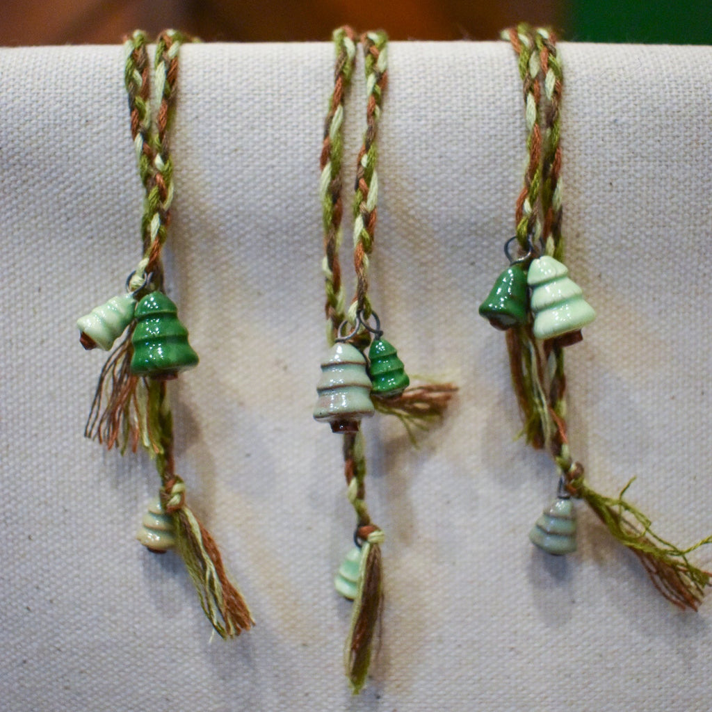 Hand-braided bookmark with hand-sculpted ceramic trees on a braided cord in greens and browns