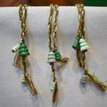 Hand-braided bookmark with hand-sculpted ceramic trees on a braided cord in greens and browns