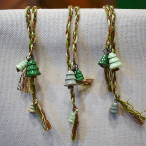 Hand-braided bookmark with hand-sculpted ceramic trees on a braided cord in greens and browns