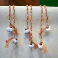 Hand-braided bookmark with hand-sculpted ceramic white pumpkins on a braided cord in red, orange, white, and green
