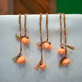 Hand-braided bookmark with hand-sculpted ceramic orange pumpkins on a braided cord in red, orange, brown, and green