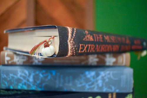 Hand-braided bookmark with hand-sculpted ceramic white pumpkins on a braided cord in red, orange, white, and green