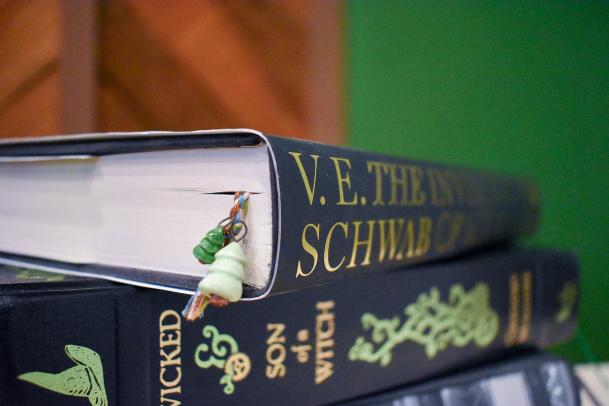 Hand-braided bookmark with hand-sculpted ceramic trees on a braided cord in green, blue, white, and brown