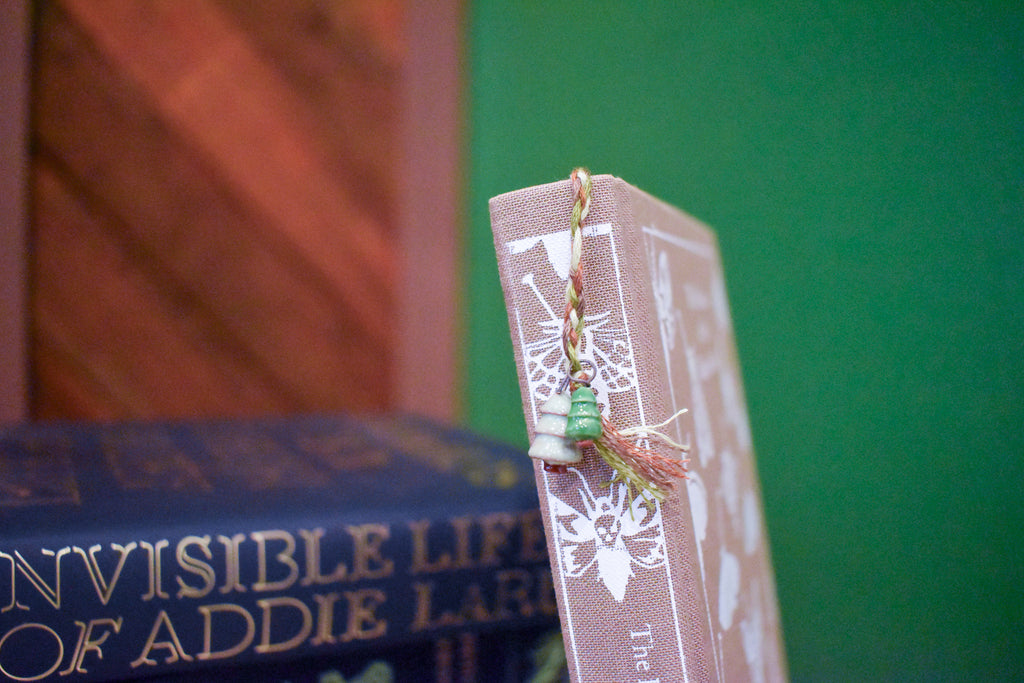 Hand-braided bookmark with hand-sculpted ceramic trees on a braided cord in greens and browns