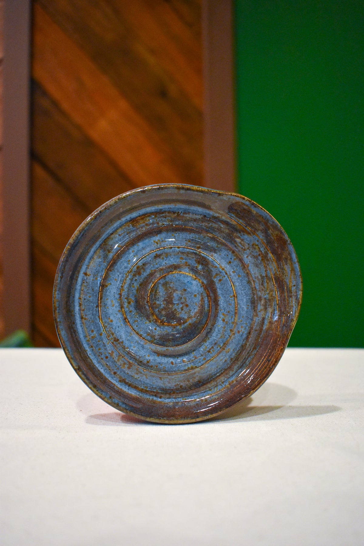 Hand-thrown spiral spoon rest in Stonewash, deep denim blue with a rust-brown rim