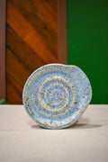 Hand-thrown spiral spoon rest in Morning Rain, soft powder blue with warm tan speckle