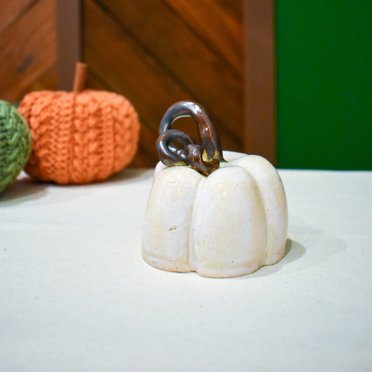 Hand-thrown ceramic pumpkin in creamy Whitewood glaze with a pewter-and-bronze vine