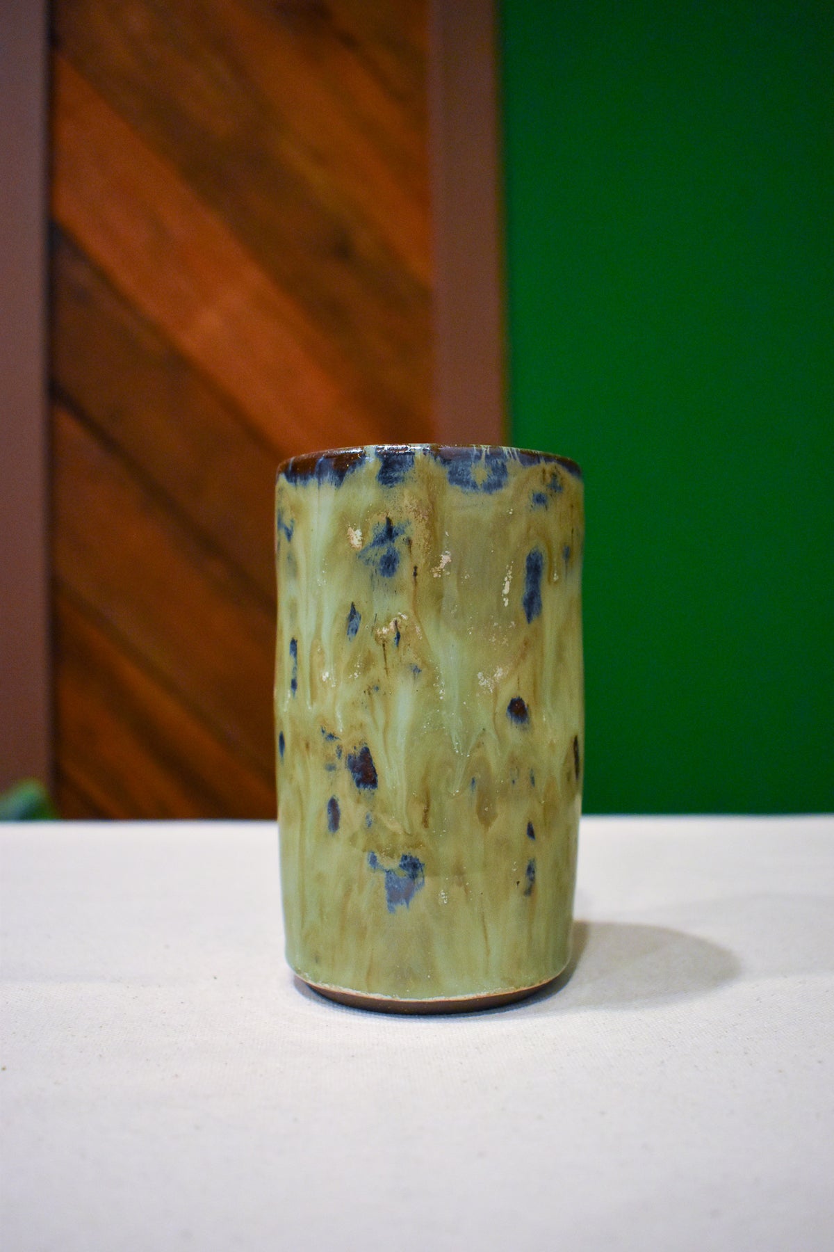 Hand-thrown ceramic travel mug in River Moss, glossy moss green with deep blue flecks