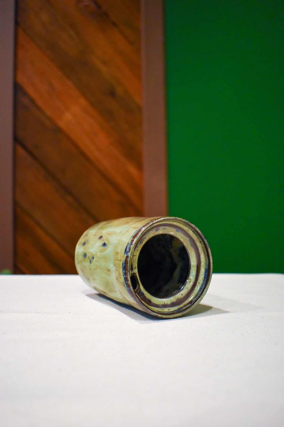 Hand-thrown ceramic travel mug in River Moss, glossy moss green with deep blue flecks