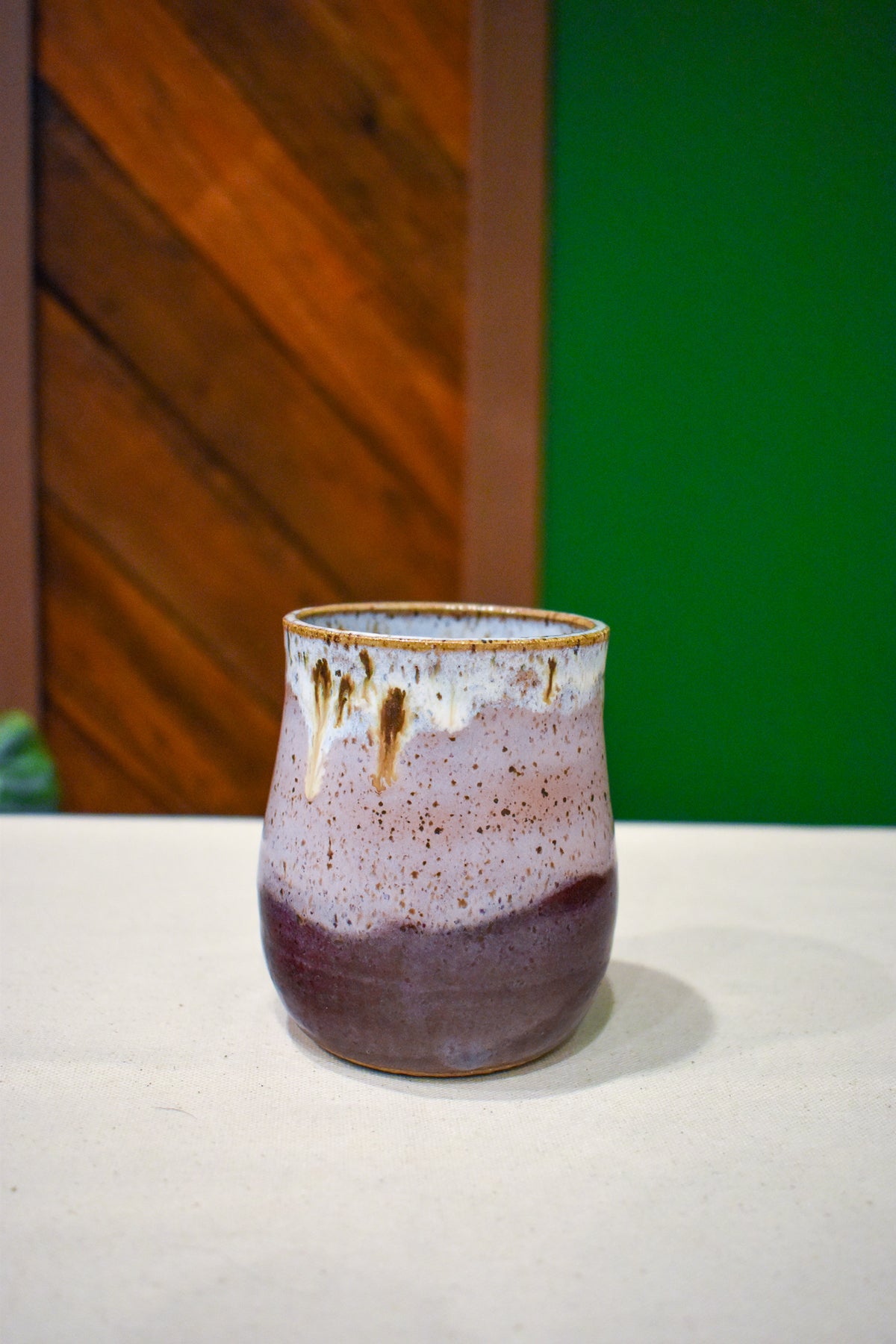 Hand-thrown handleless cup in Orchard Mist, soft white drips over lilac and plum