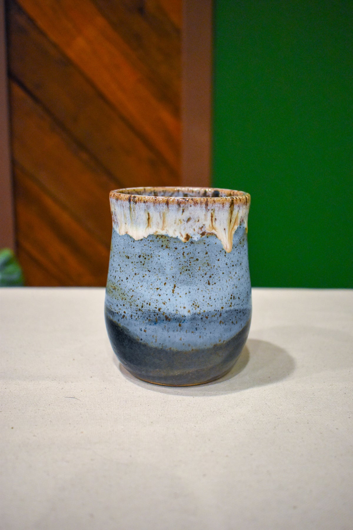 Hand-thrown handleless cup in Lakeshore, soft white drips over sky blue and slate navy