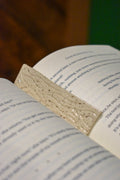 Hand-formed stoneware bookmark with carved wood-grain lines under a creamy white glaze, clean, squared ends