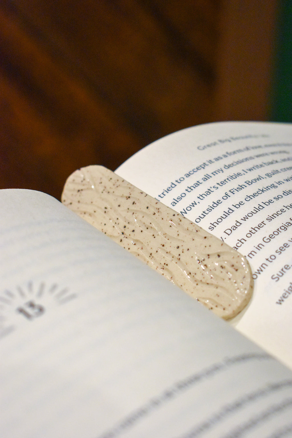 Hand-formed stoneware bookmark with carved wood-grain lines under a creamy white glaze, softly rounded ends