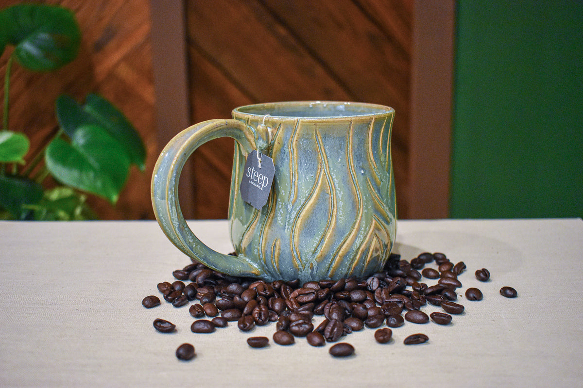 Hand-thrown mug carved with bark-like grain lines in Ivy, sage and soft blue-grey glaze with honey-gold highlights