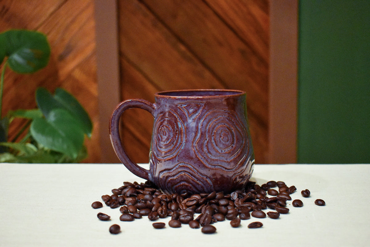 Hand-thrown mug with carved topographic ridges in Deep Plum, dusty rose to lavender at the rim with rust in the carved lines