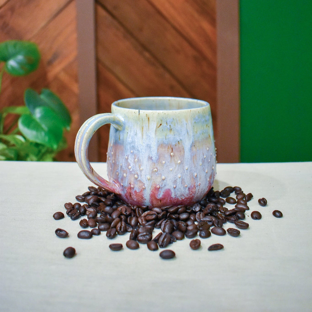 Hand-thrown mug in Sunset Tide, cream and pale blue at the rim drifting through lavender to deep raspberry pink at the base