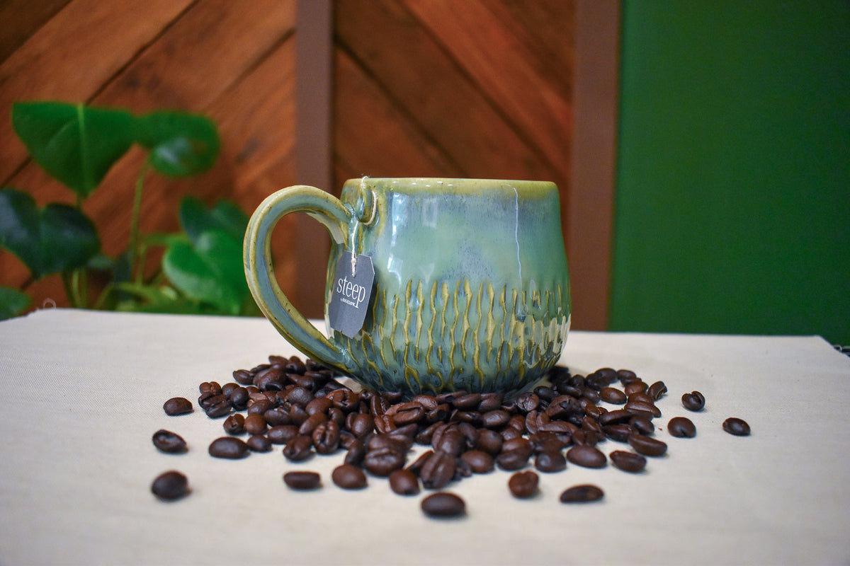 Hand-thrown mug with overlapping pointed carved marks in Pinescale, forest green from bright jade to olive gold