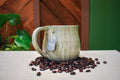 Hand-thrown mug carved with bark-like grain lines in Mosswood, layered sage and warm earth-brown glaze