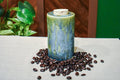 Hand-thrown ceramic travel mug in Creekstone with a cork stopper, deep olive over mottled teal, slate blue and moss