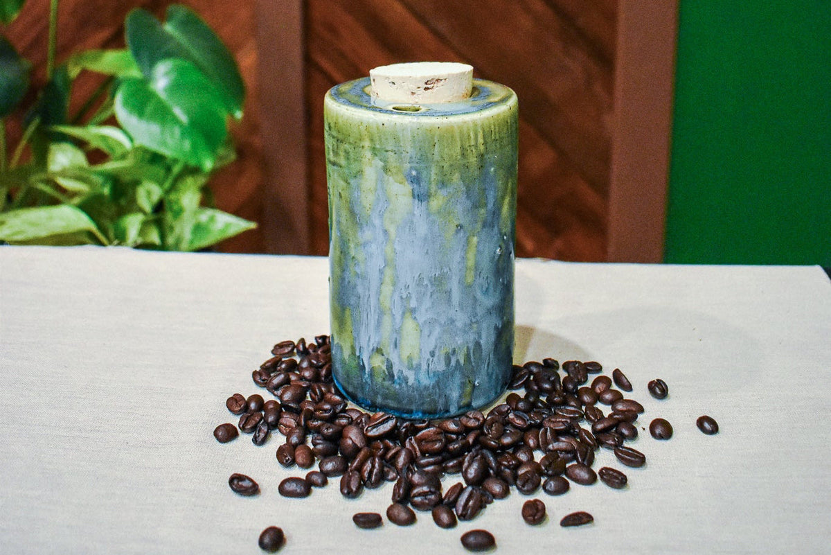 Hand-thrown ceramic travel mug in Creekstone with a cork stopper, deep olive over mottled teal, slate blue and moss